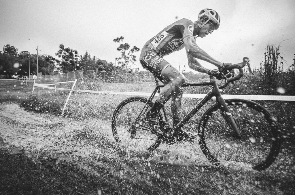 Wayne Keller cyclocross athlete riding through the mud making a big splash