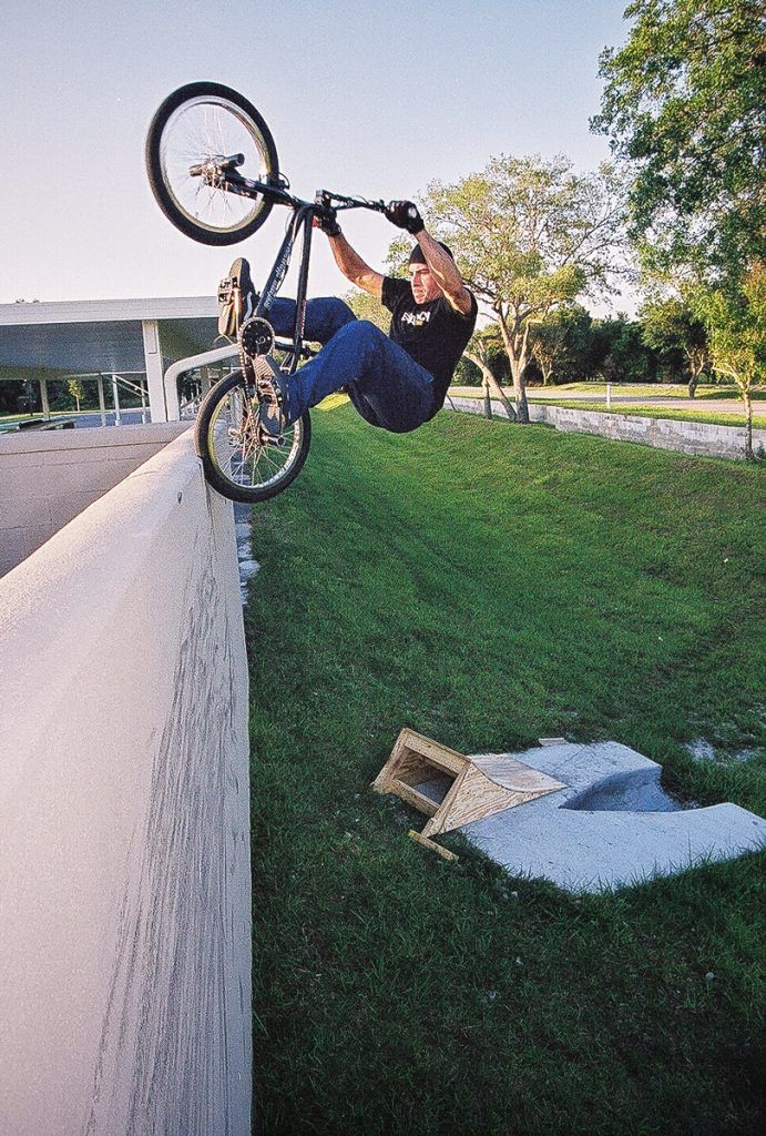 Mike Andrews, BMX Freestyler, jumping out of a ramp and stalling on a wall