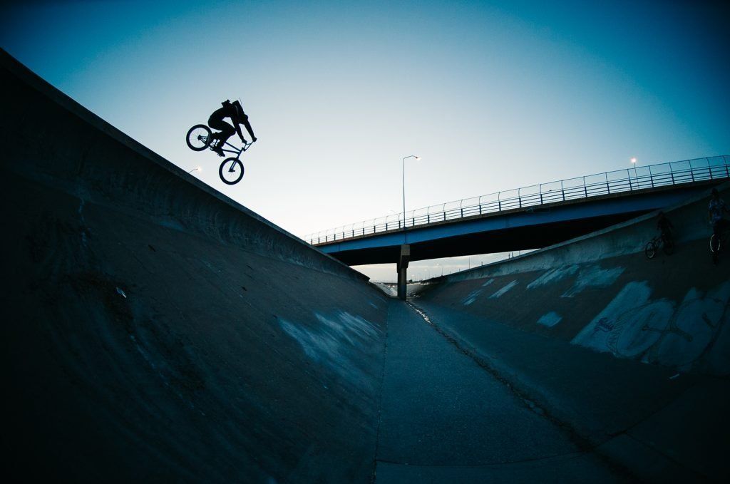 Cyclist Karl Poynter jumping his bike into a concrete water retention ditch