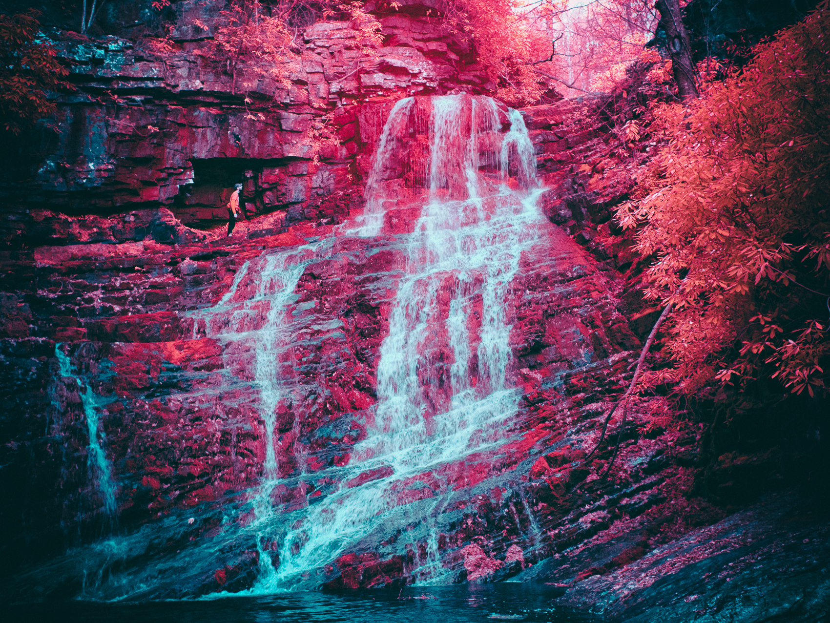 An infrared image of a hiker scaling Margarette Falls in Tennessee